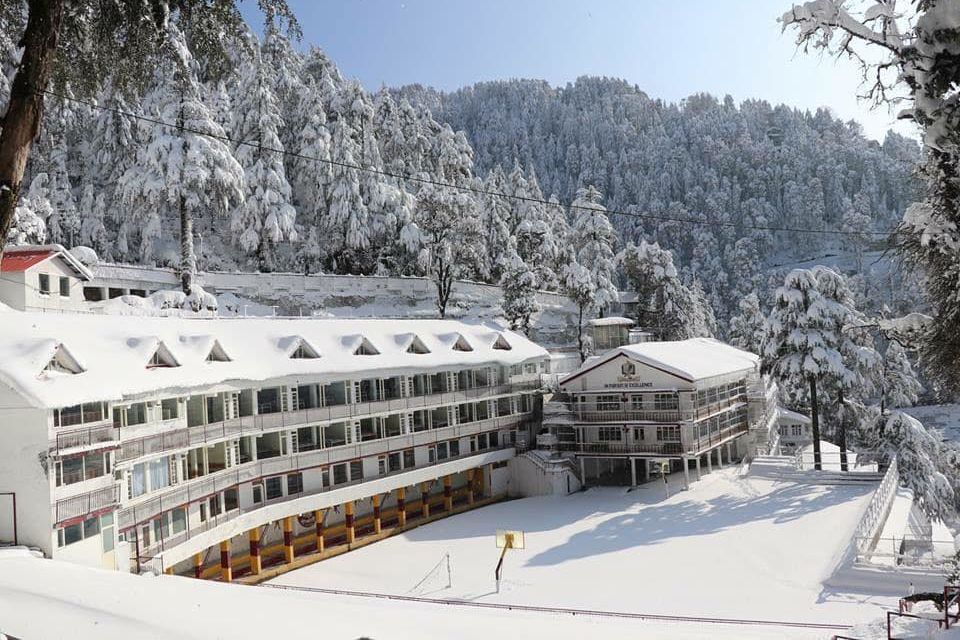 a building covered in snow with pine trees covered in snow in banikhet