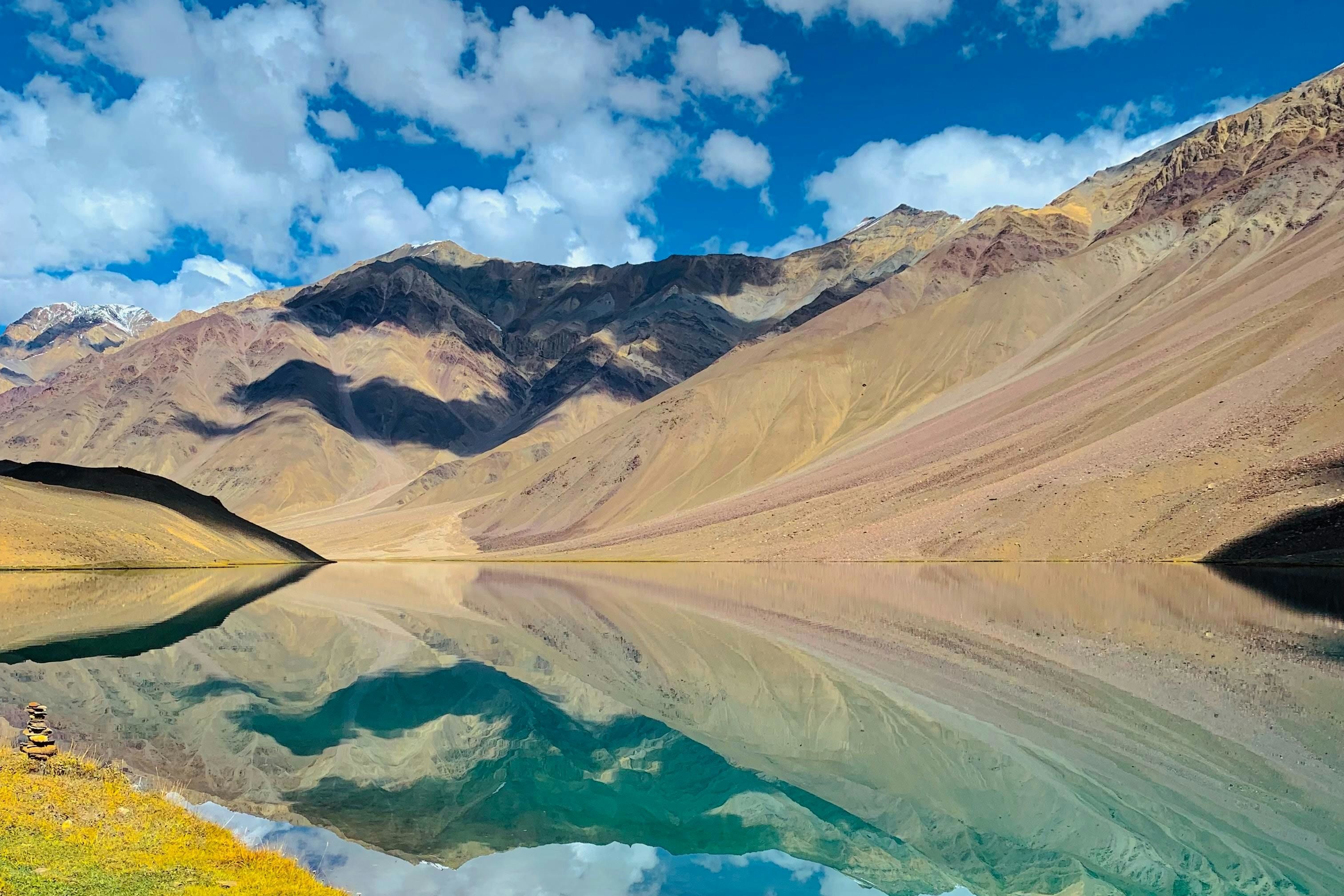 blue coloured water in chandra taal lake surrounded by mountains
