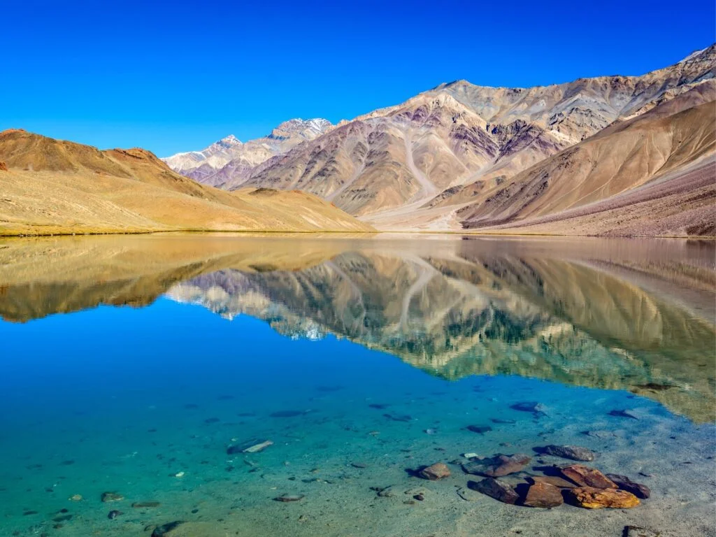 chandratal lake in the foreground of mountains in daylight