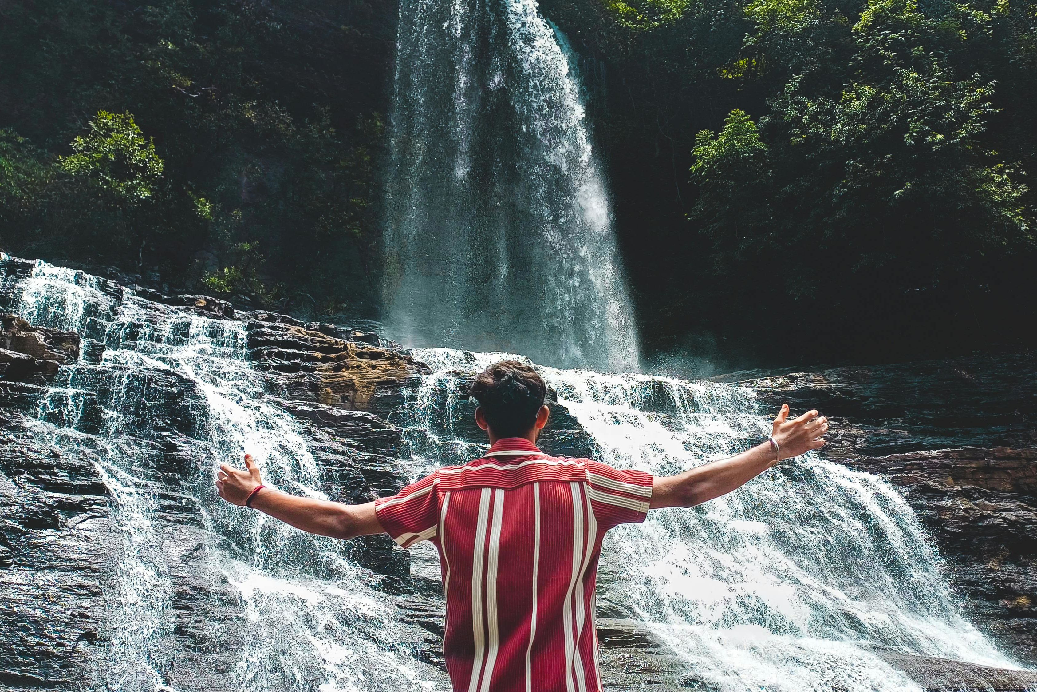a man embracing nature at bhagsu waterfall in dharamshala