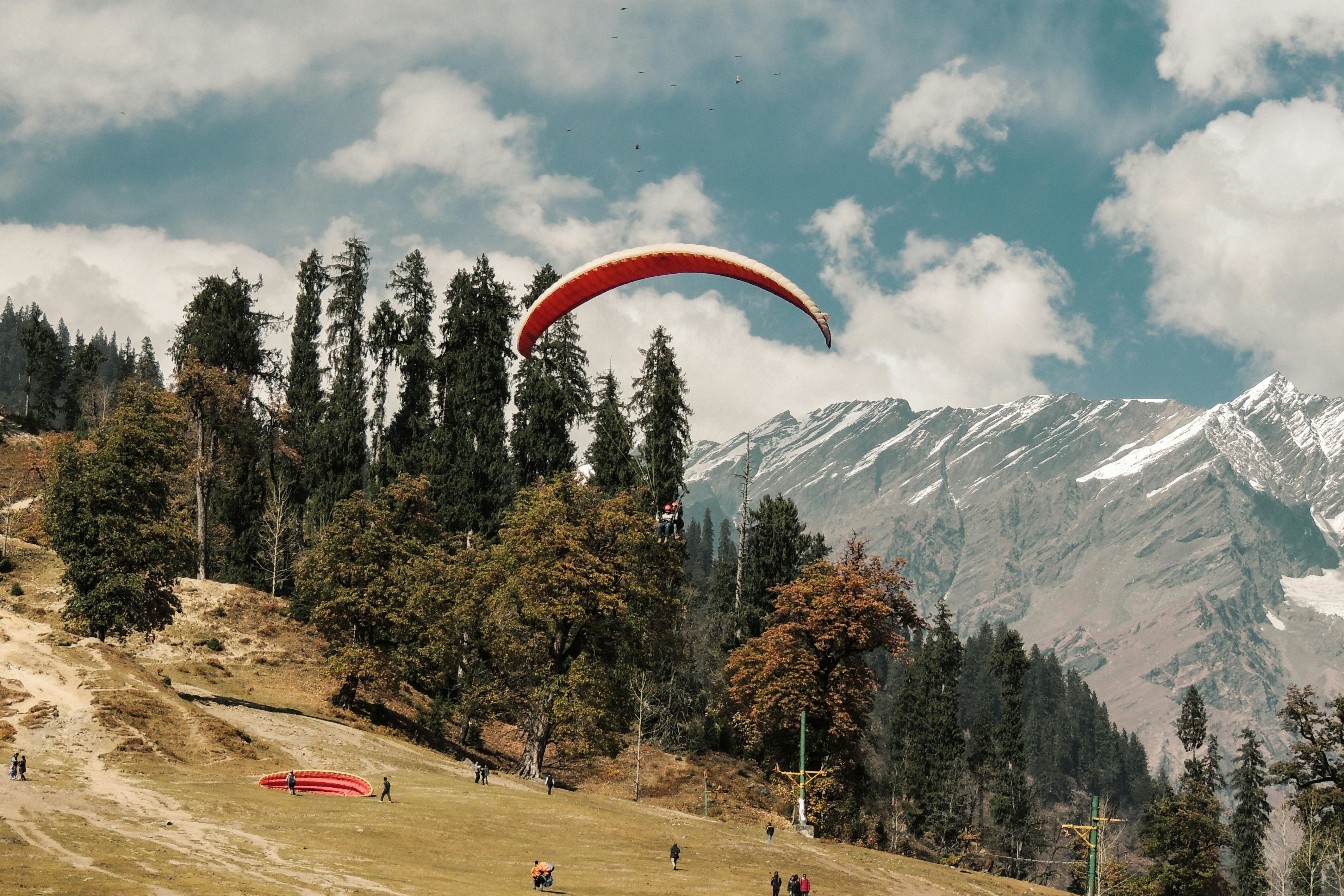 paragliding at solang valley under cloudy blue sky