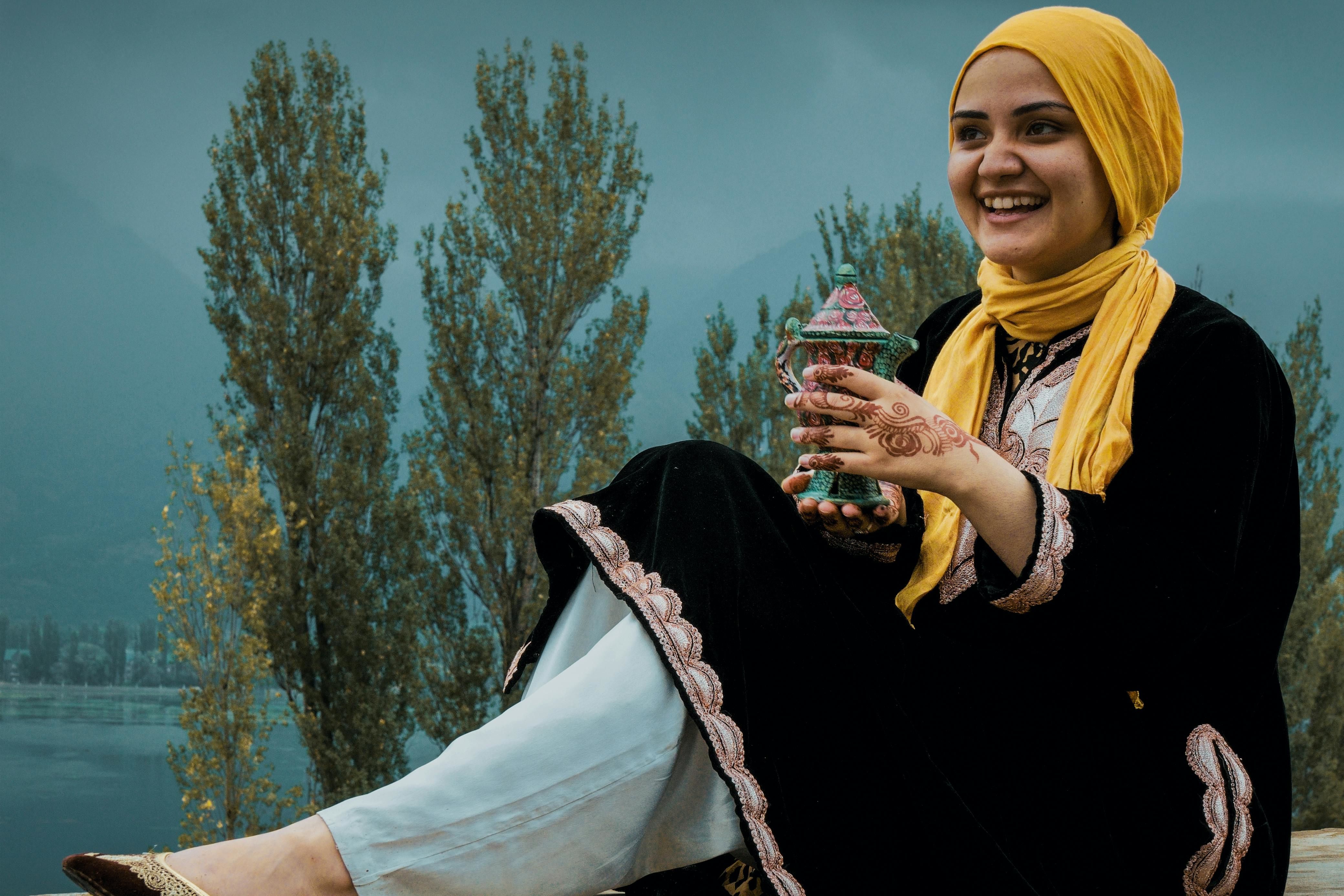 a smiling woman in hijab sitting on wall in srinagar