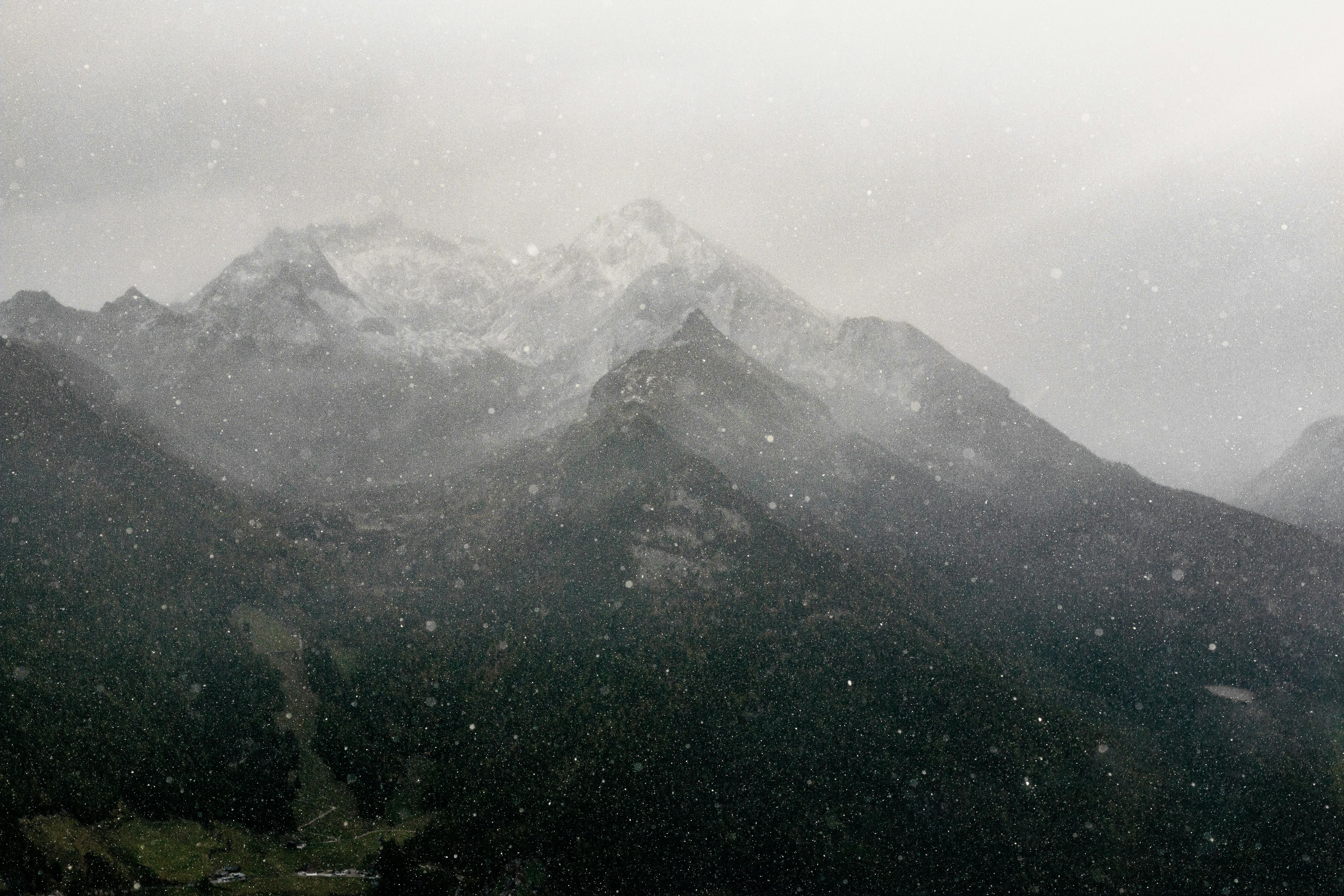 snowfall near black and gray mountains