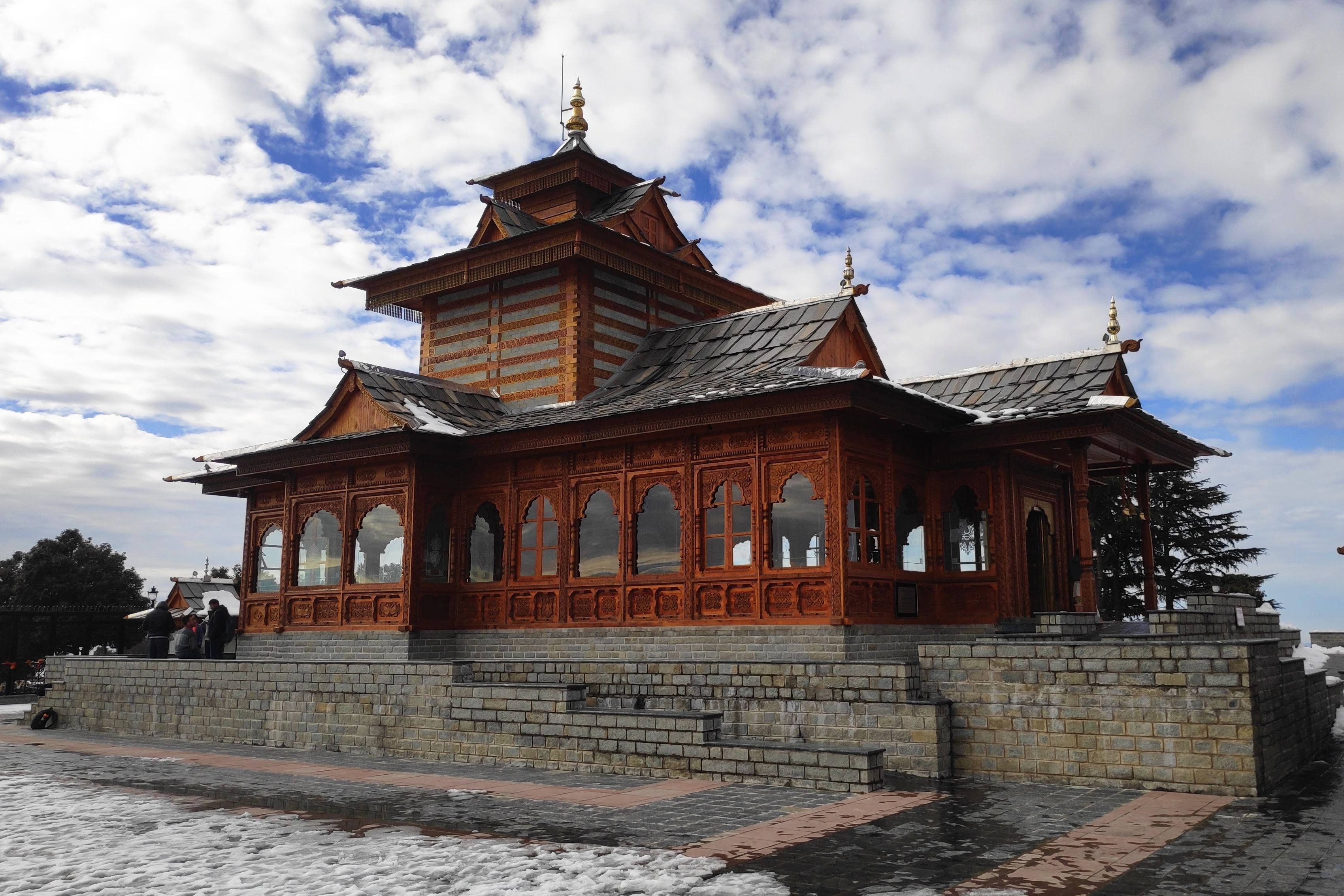 a view of tara devi temple in shimla with white clouds in the backdrop