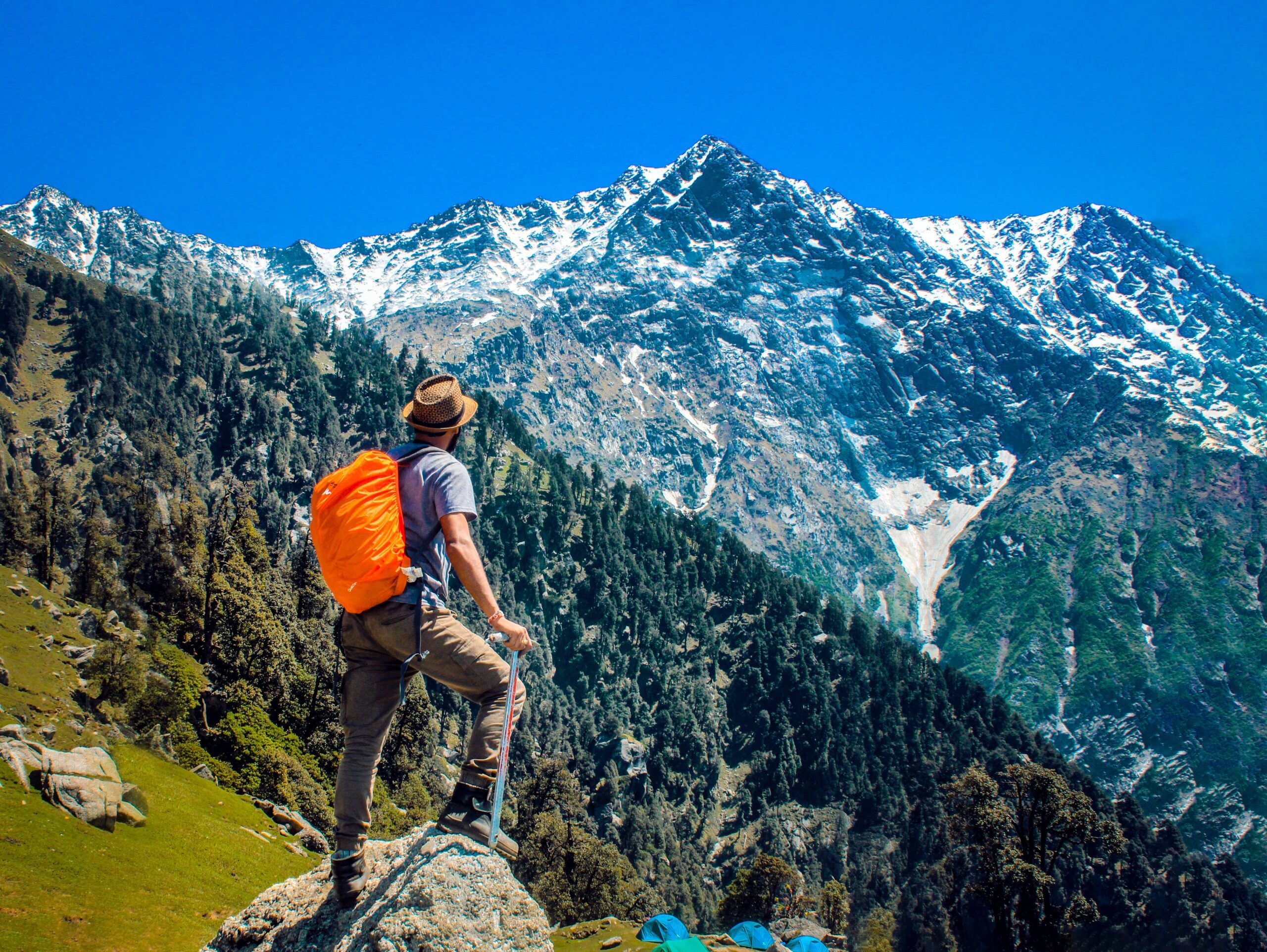 a person standing on a rock with snow covered mountains in the backdrop