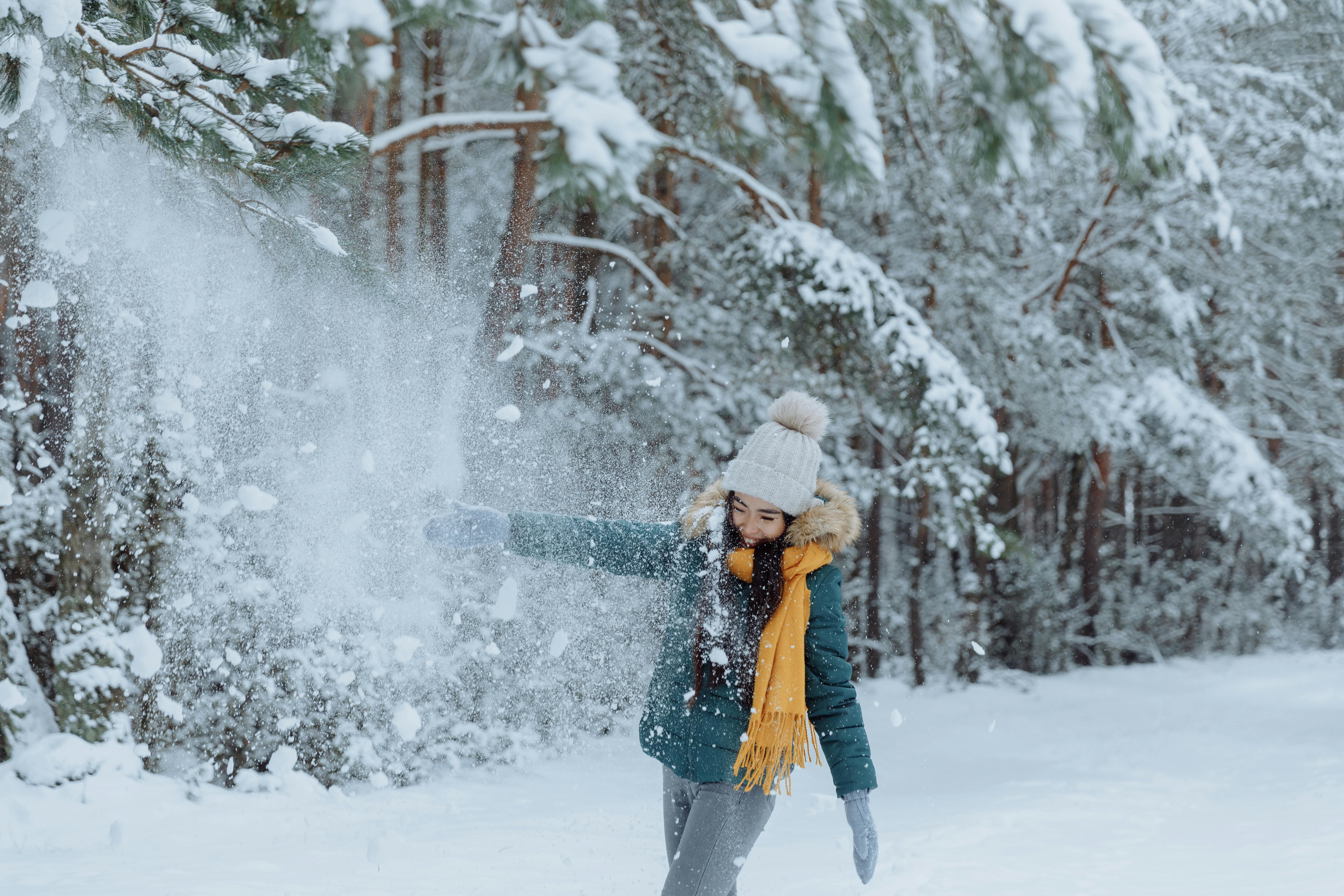 woman in green jacket playing with snow